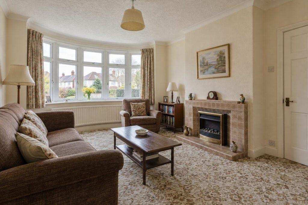 Living room in a dated but clean 1930s semi, magnolia walls and original kitchen