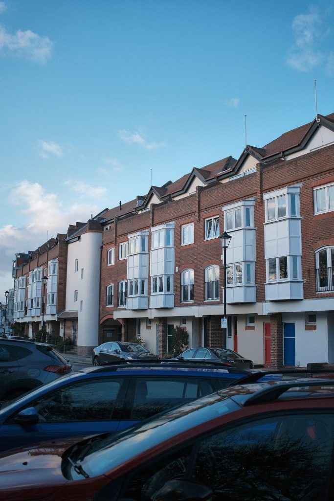 Modern red brick townhouse terrace with white bay windows and coloured front doors