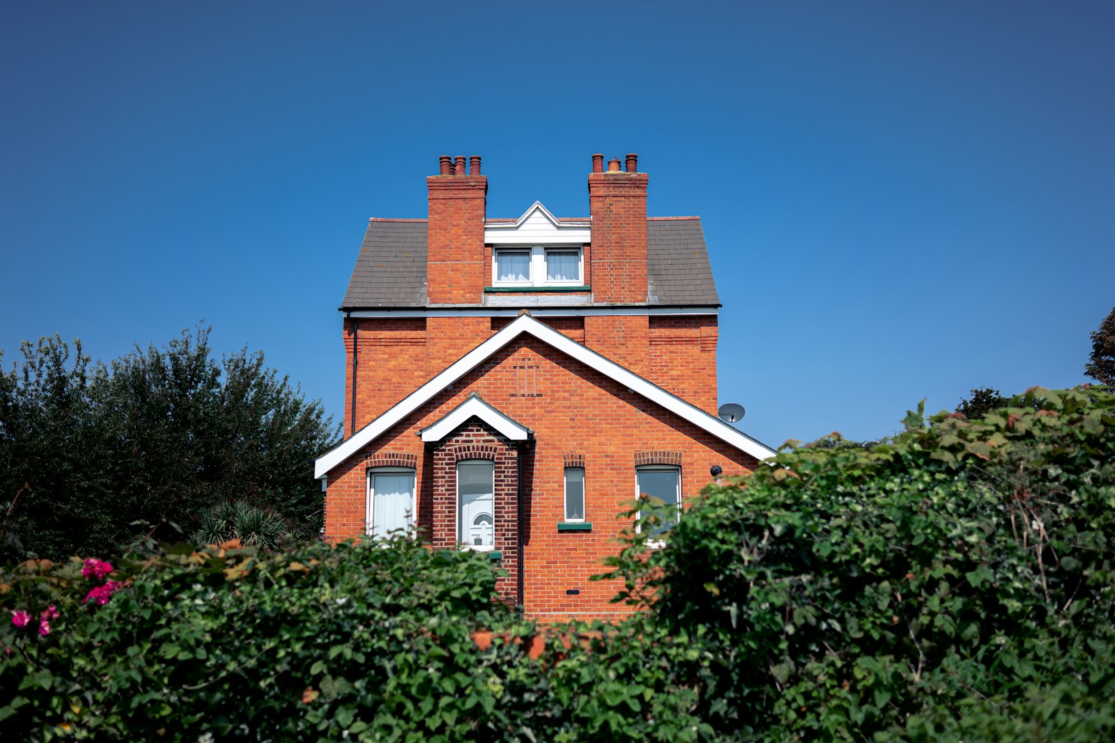 Red brick Victorian villa with gabled porch and twin chimneys