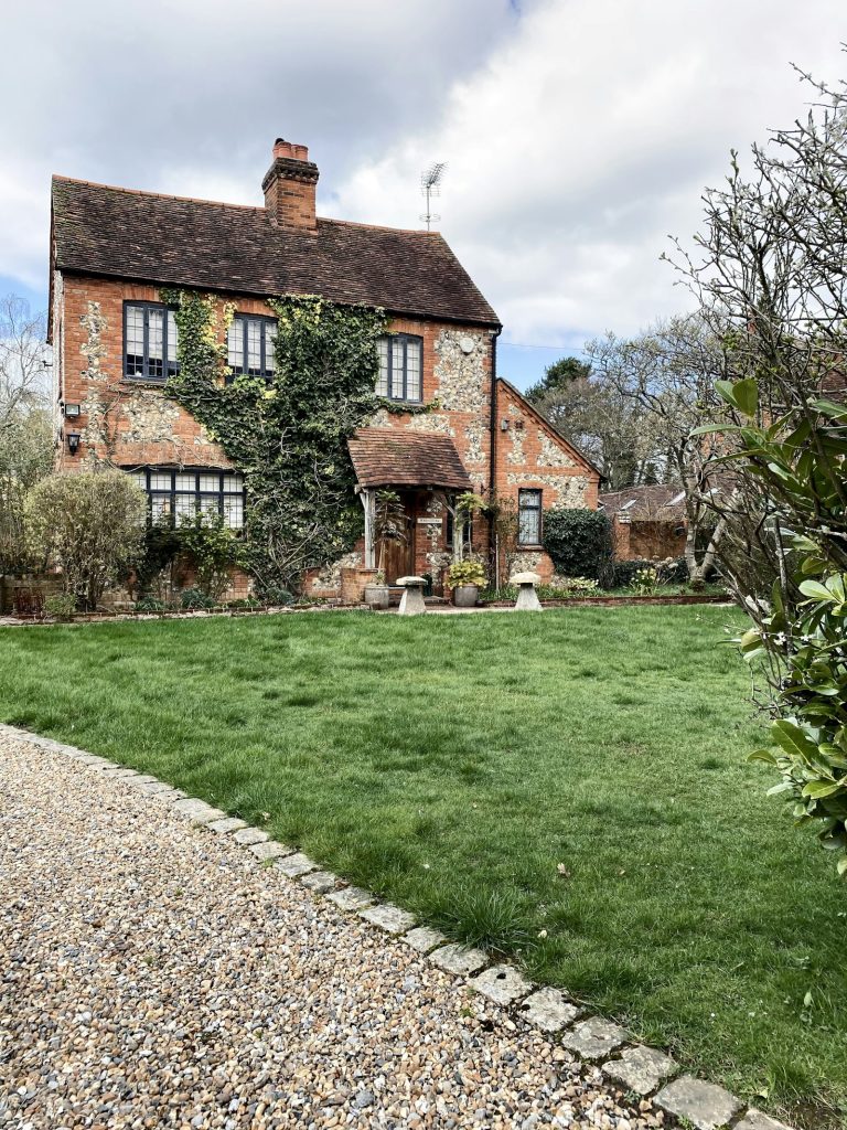 Brick and flint cottage with ivy and a gravel drive