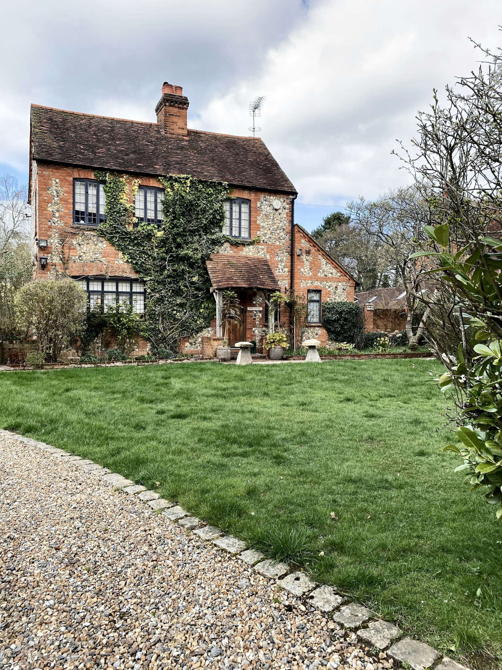 Brick and flint cottage with ivy and a gravel drive