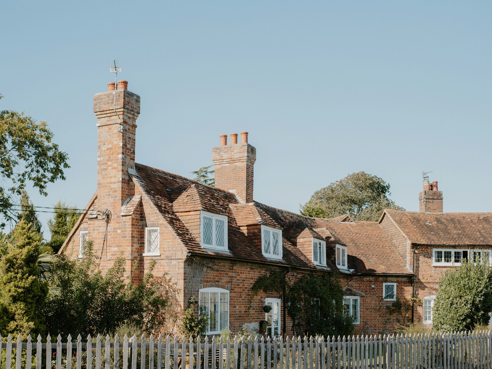 Red brick cottages with dormer windows behind a picket fence
