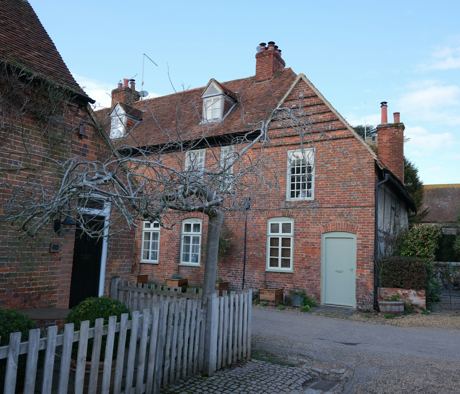 Red brick cottage with dormer window and pale green door