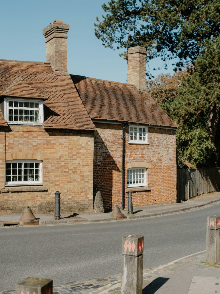Old brick cottage with white windows and two chimneys