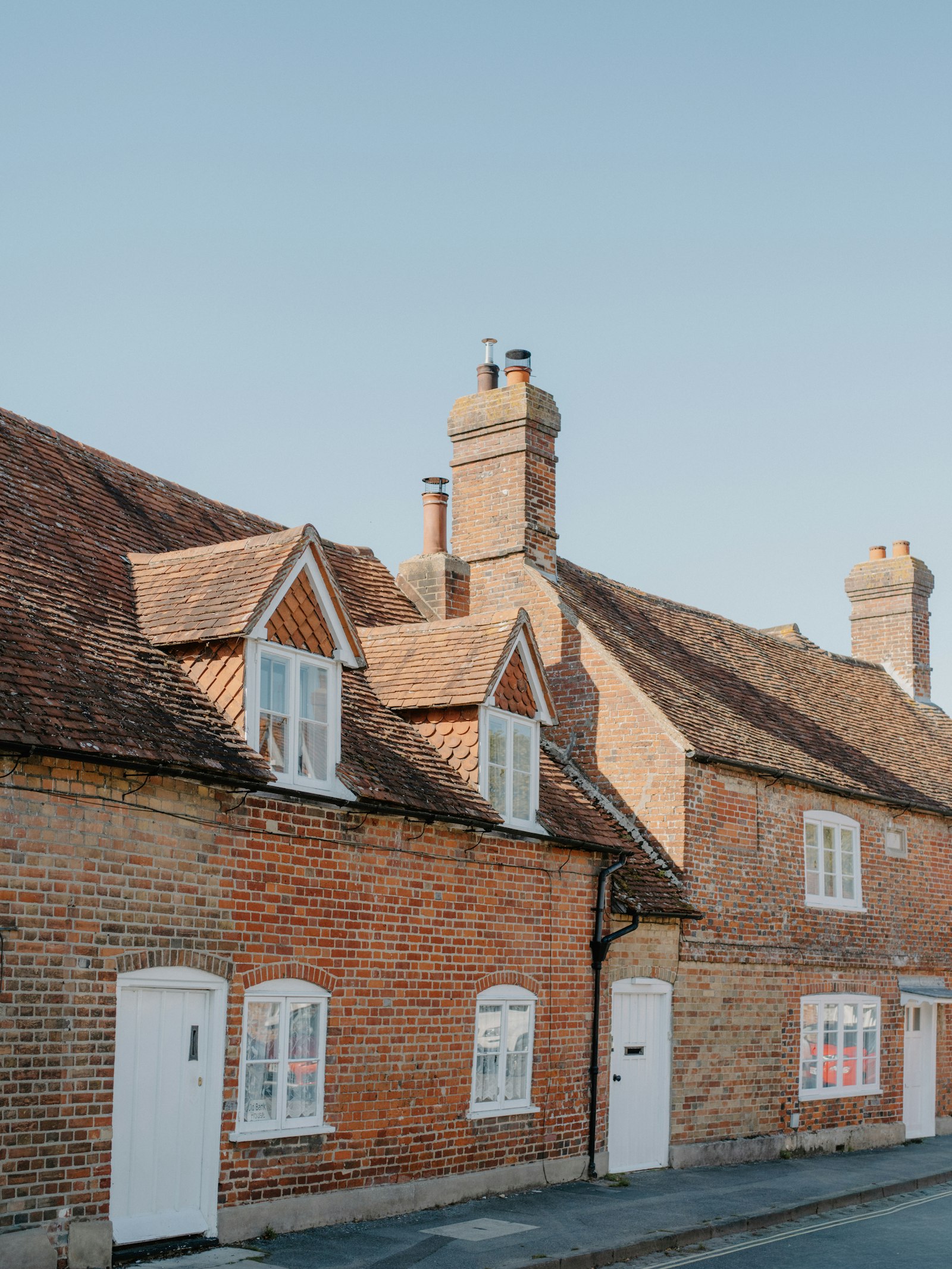 Row of red brick cottages with dormers and white doors