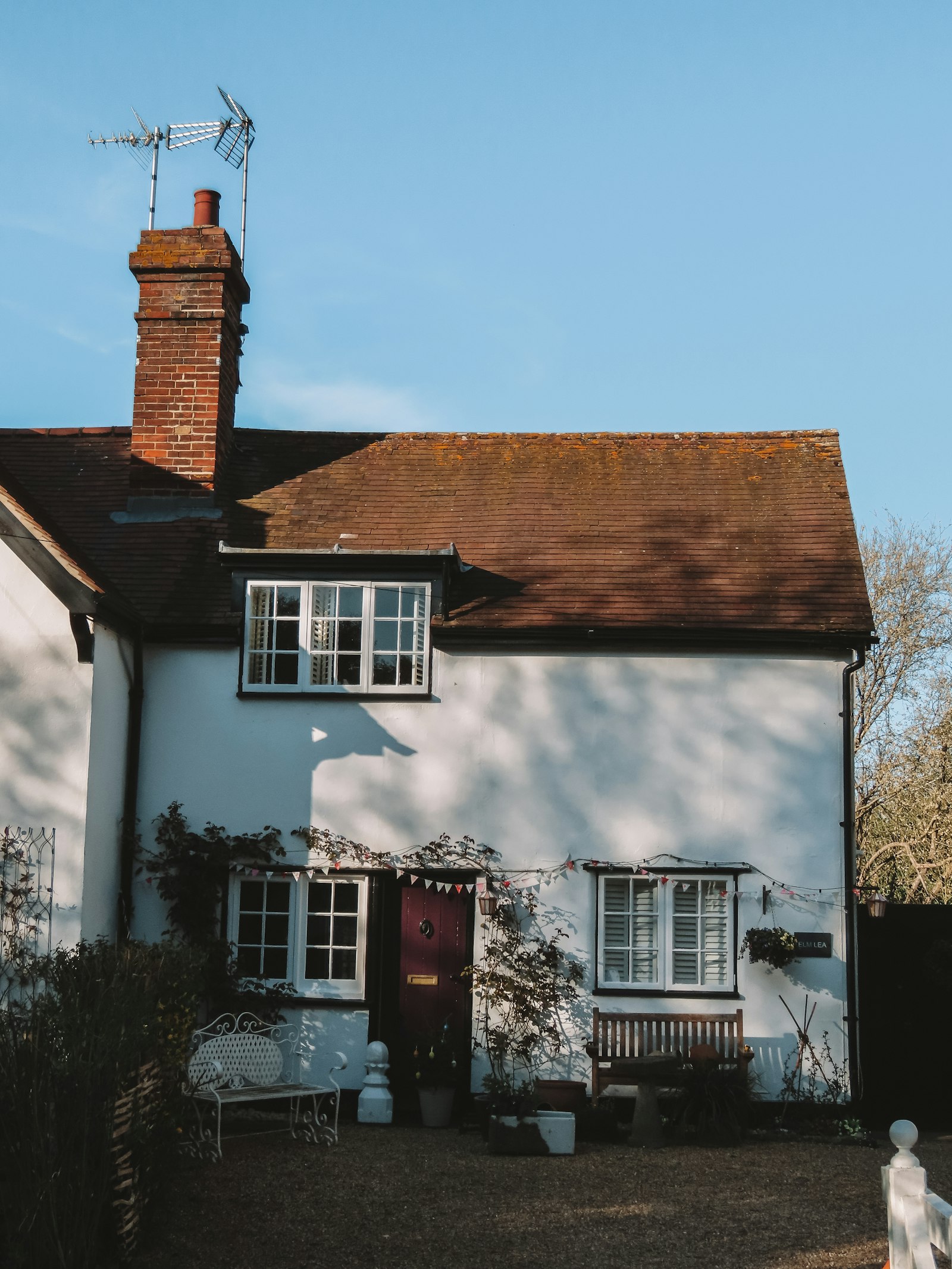 White rendered cottage with tiled roof and brick chimney