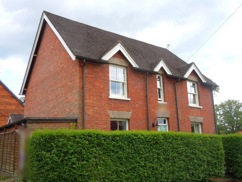 Red brick Victorian detached house with white-trimmed gables and sash windows behind a clipped hedge, Chiddingfold, Surrey