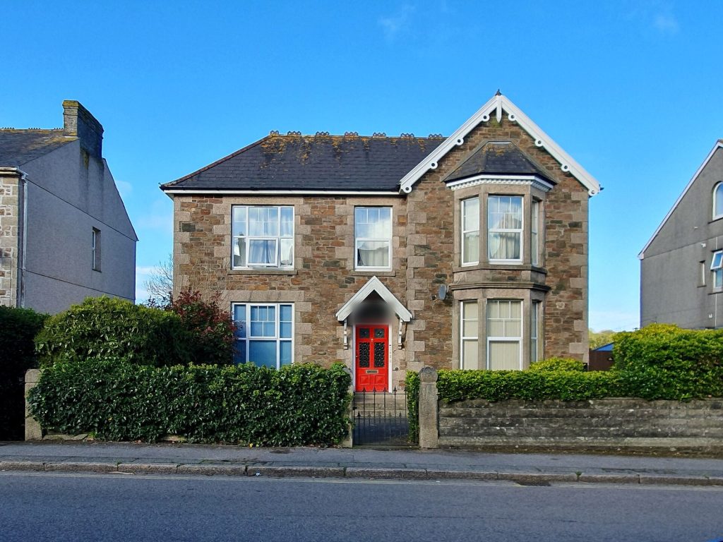 Granite Victorian detached villa with a white bargeboarded gable, bay window and red front door