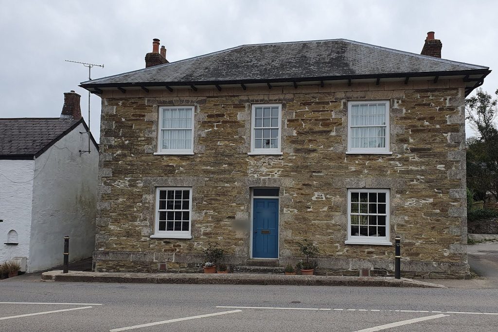 Symmetrical Georgian stone detached house with hipped slate roof, sash windows and a blue front door