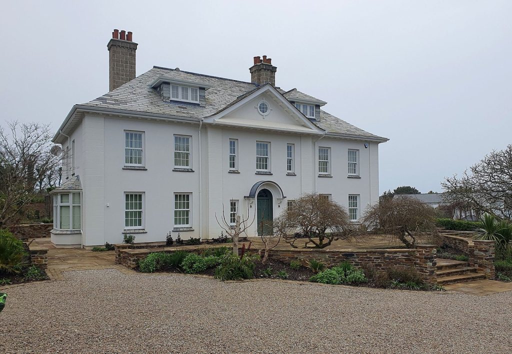 White neo-Georgian detached house with pedimented centre, slate roof and gravel drive