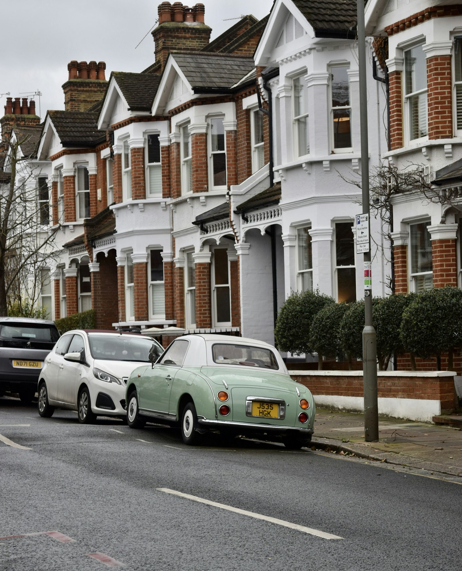 Edwardian terrace with bay windows and cars parked on the street