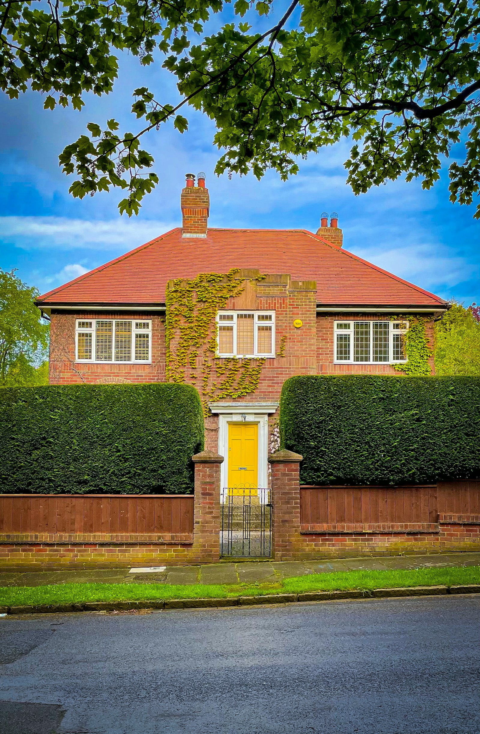 1930s brick house with a red tiled roof and yellow front door