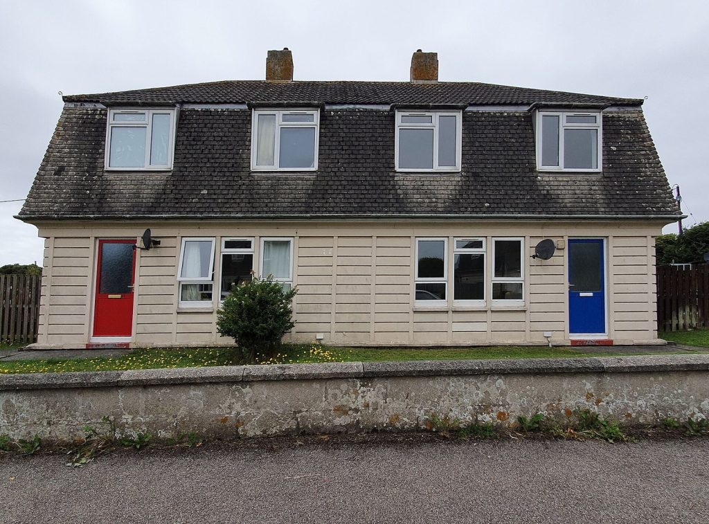 Postwar mansard-roofed semi-detached pair with red and blue doors, Helston, Cornwall