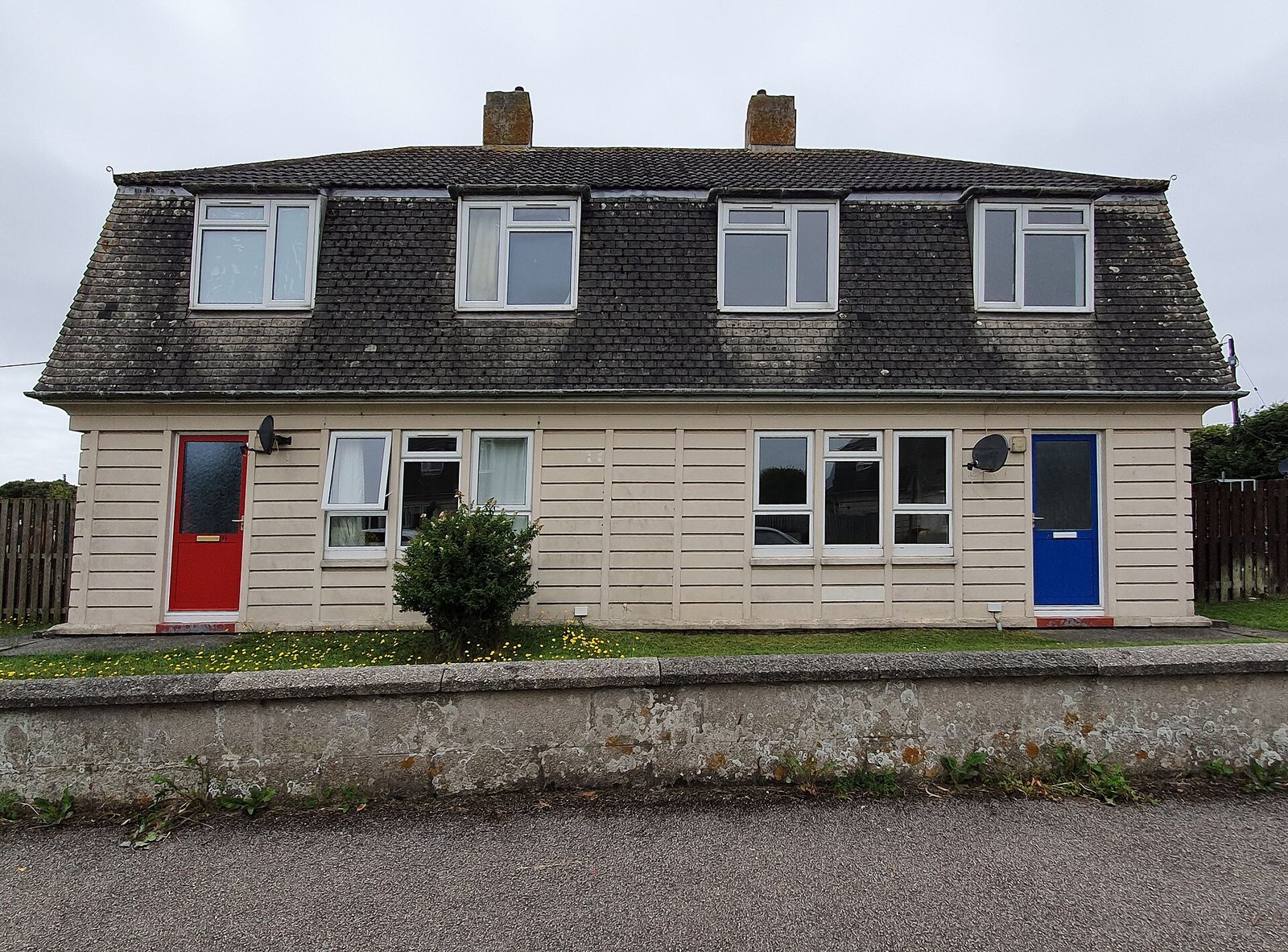 Postwar mansard-roofed semi-detached pair with red and blue doors, Helston, Cornwall