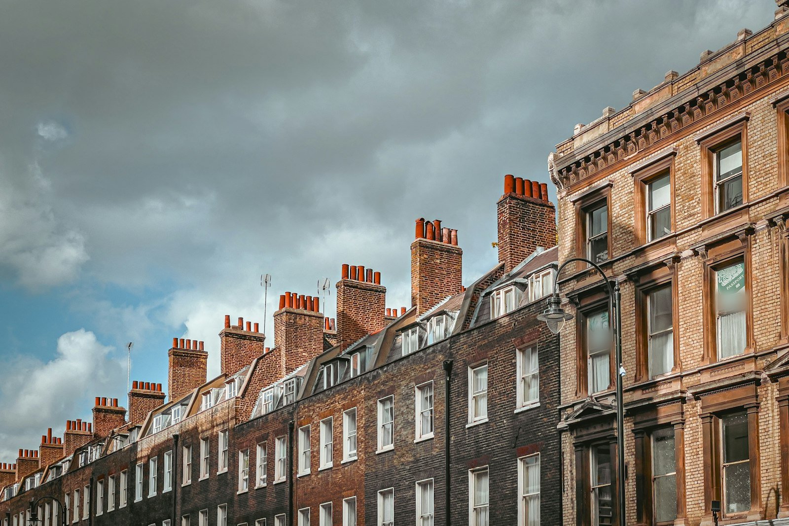 Row of red brick Victorian terraces with tall chimney stacks under a cloudy sky