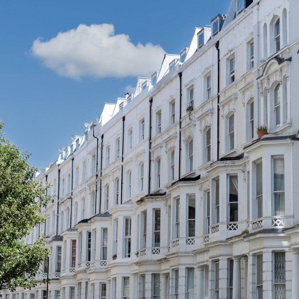 Row of white stucco Victorian terraces with bay windows under a blue sky